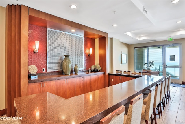 kitchen with visible vents, dark stone counters, a breakfast bar area, and recessed lighting