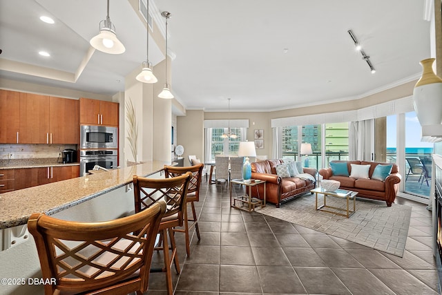 kitchen featuring tasteful backsplash, brown cabinetry, appliances with stainless steel finishes, ornamental molding, and dark tile patterned floors