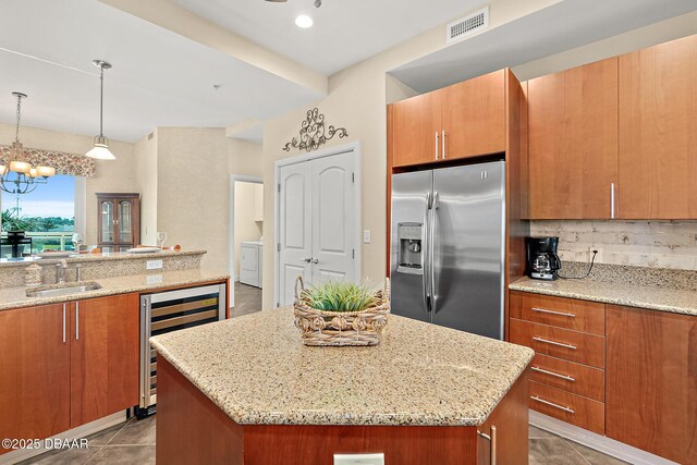 kitchen featuring wine cooler, a sink, stainless steel fridge with ice dispenser, backsplash, and brown cabinets