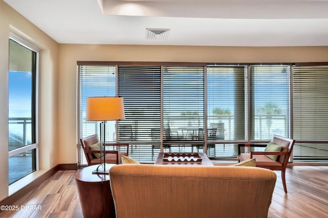 living area featuring light wood-style flooring, visible vents, and baseboards