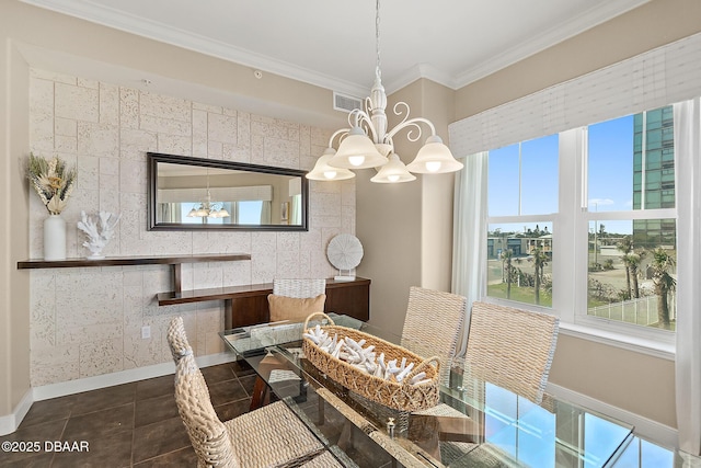 dining space featuring dark tile patterned flooring, crown molding, baseboards, and an inviting chandelier