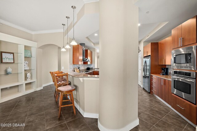 kitchen featuring wall chimney exhaust hood, appliances with stainless steel finishes, dark tile patterned floors, and a breakfast bar