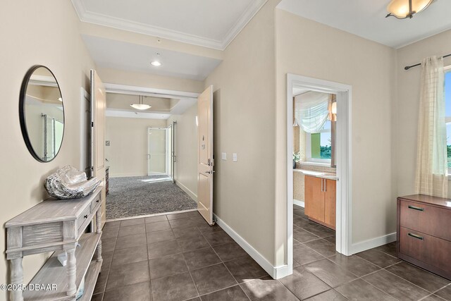 hall featuring baseboards, crown molding, and dark tile patterned flooring