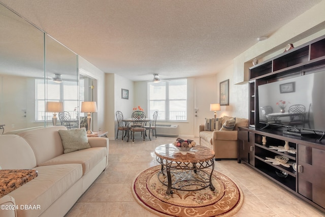 living room featuring light tile patterned flooring, ceiling fan, a textured ceiling, and a wall mounted AC