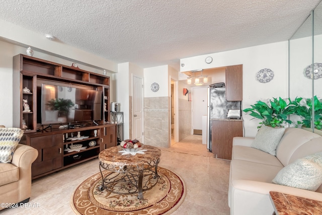 living room with tile walls, a textured ceiling, and light tile patterned floors