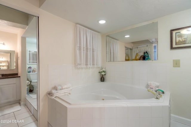 bathroom featuring a relaxing tiled tub, tile patterned floors, vanity, and toilet