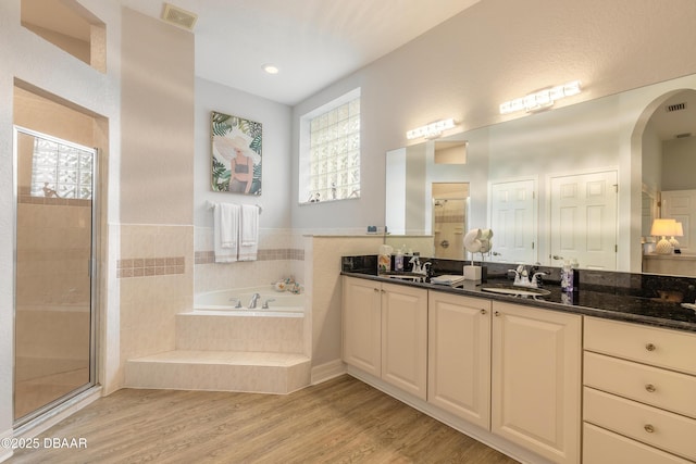 bathroom with vanity, hardwood / wood-style floors, and plus walk in shower