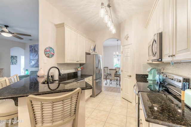 kitchen with appliances with stainless steel finishes, a breakfast bar, pendant lighting, light tile patterned floors, and kitchen peninsula