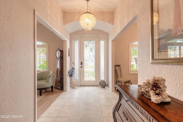 tiled foyer featuring an inviting chandelier and plenty of natural light