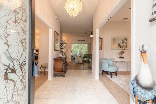 hall with light tile patterned flooring and a notable chandelier