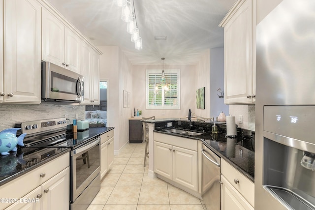 kitchen with sink, decorative light fixtures, dark stone countertops, stainless steel appliances, and decorative backsplash