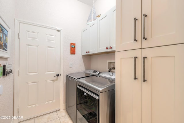 washroom with cabinets, washing machine and clothes dryer, and light tile patterned flooring