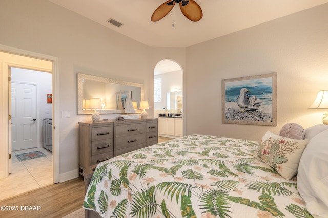 bedroom featuring ceiling fan, connected bathroom, washer / dryer, and light wood-type flooring