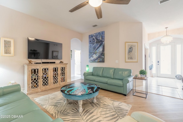 living room with ceiling fan with notable chandelier and light wood-type flooring