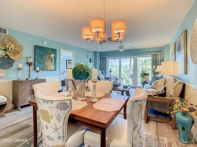 dining room with ceiling fan with notable chandelier and light hardwood / wood-style flooring