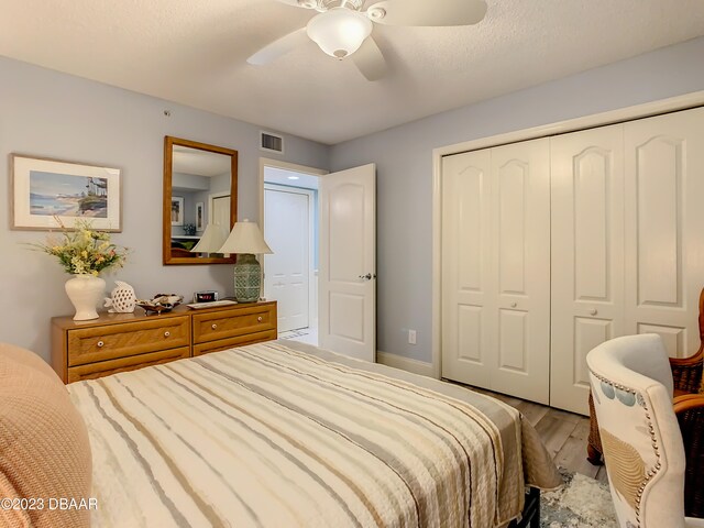 bedroom with light hardwood / wood-style floors, ceiling fan, a textured ceiling, and a closet