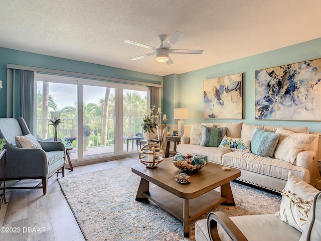 living room featuring ceiling fan, a textured ceiling, and light wood-type flooring