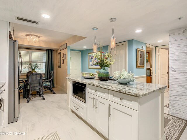 kitchen featuring tile walls, white cabinetry, appliances with stainless steel finishes, pendant lighting, and light stone countertops