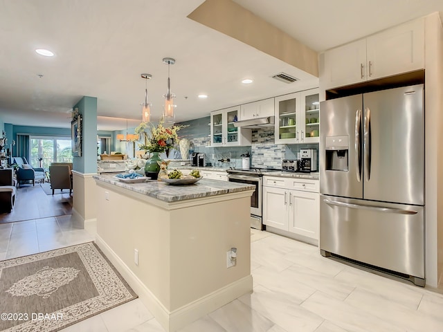 kitchen featuring white cabinets, stainless steel appliances, light stone counters, and backsplash