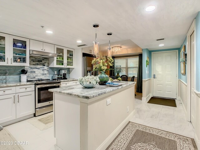 kitchen featuring stainless steel appliances, pendant lighting, light stone counters, a kitchen island, and white cabinetry