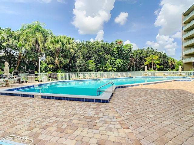 4 Oceans W Blvd Unit 307D, Daytona Beach Shores, FL 32118 - community pool featuring a patio area, fence, and view of wooded area