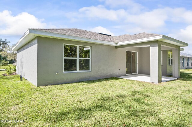 30 Peppercorn Ln, Palm Coast, FL 32164 - rear view of house featuring a patio, a shingled roof, a lawn, and stucco siding