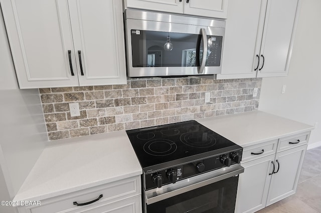 30 Peppercorn Ln, Palm Coast, FL 32164 - kitchen with stainless steel microwave, black range with electric cooktop, white cabinetry, light countertops, and tasteful backsplash