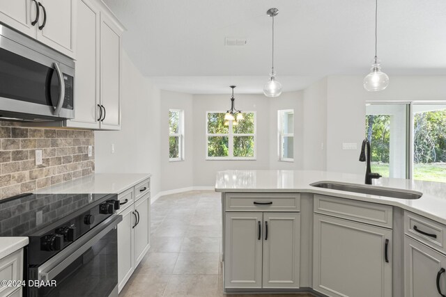 30 Peppercorn Ln, Palm Coast, FL 32164 - kitchen featuring black electric range oven, stainless steel microwave, a sink, tasteful backsplash, and light countertops