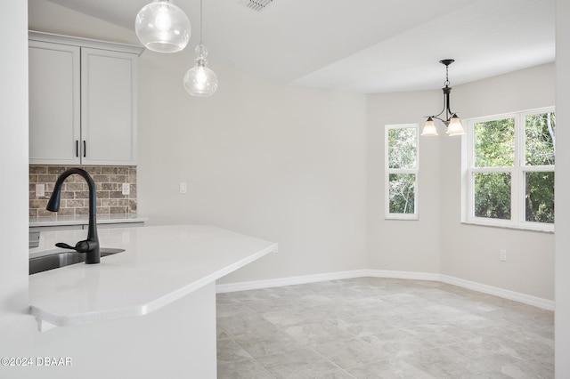 30 Peppercorn Ln, Palm Coast, FL 32164 - kitchen with a sink, light countertops, hanging light fixtures, baseboards, and backsplash