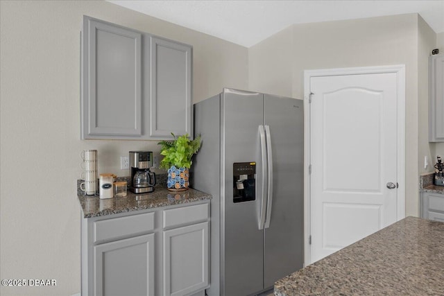 kitchen featuring gray cabinets, stainless steel fridge with ice dispenser, and dark stone counters