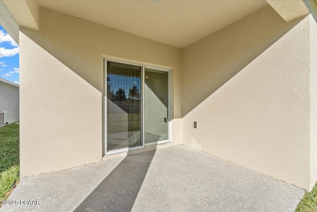 view of exterior entry with central AC unit and a patio area