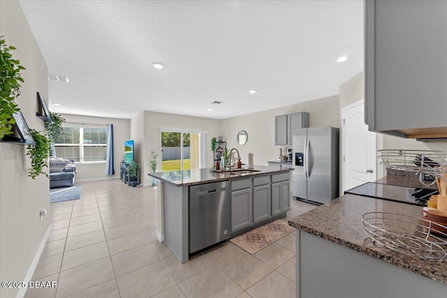 kitchen featuring gray cabinets, sink, stainless steel appliances, and a kitchen island with sink