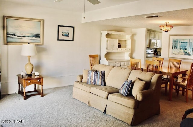 carpeted living room with ceiling fan and a textured ceiling