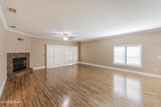 unfurnished living room featuring a ceiling fan, visible vents, wood finished floors, baseboards, and ornamental molding