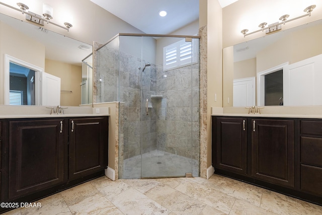 full bathroom with two vanities, a shower stall, and a sink