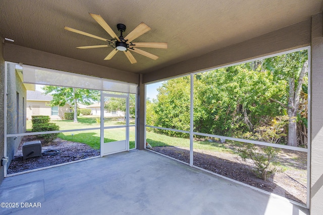 unfurnished sunroom featuring a ceiling fan and a wealth of natural light