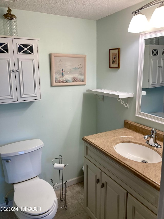 bathroom featuring toilet, vanity, a textured ceiling, and tile patterned floors