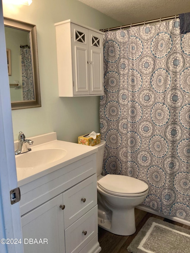 bathroom with toilet, vanity, a textured ceiling, and hardwood / wood-style flooring