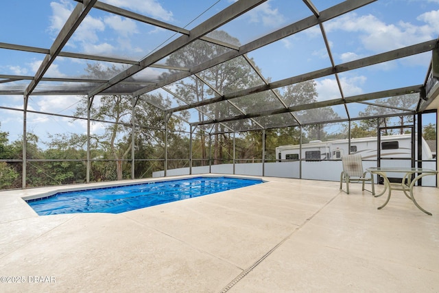 outdoor pool featuring glass enclosure and a patio