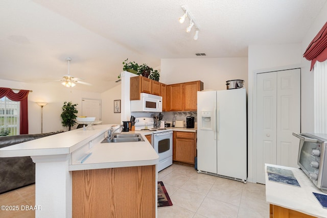 kitchen featuring visible vents, a sink, white appliances, a peninsula, and light countertops