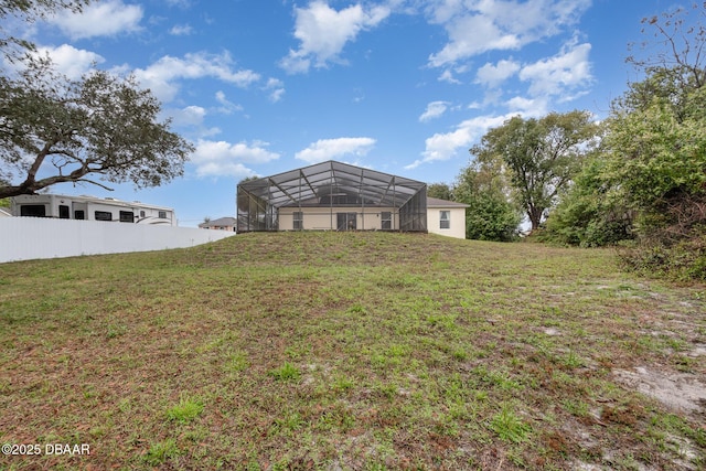 rear view of property featuring glass enclosure, a yard, and fence