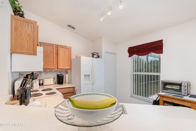 kitchen featuring visible vents, light countertops, vaulted ceiling, white appliances, and a textured ceiling