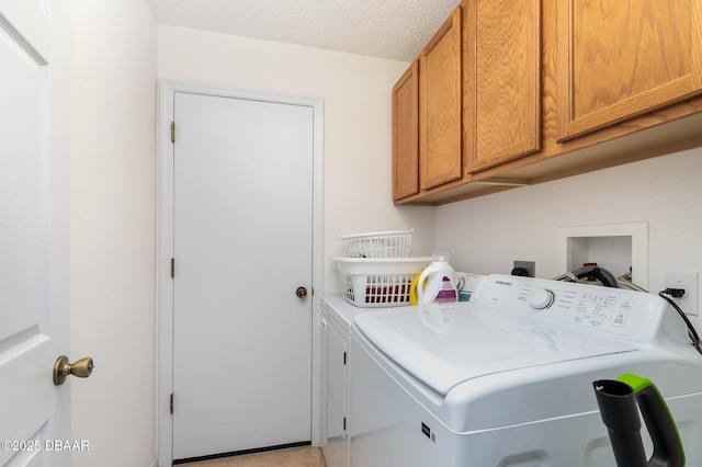 washroom featuring cabinet space, a textured ceiling, and washing machine and dryer