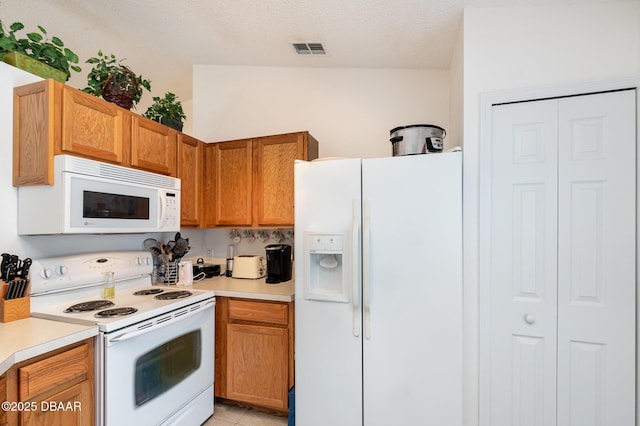 kitchen with visible vents, white appliances, a textured ceiling, and light countertops