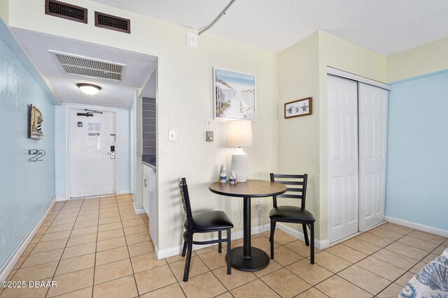 hall with light tile patterned floors, visible vents, and a textured ceiling