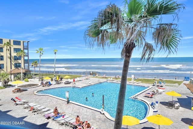 community pool with a patio, a water view, and fence