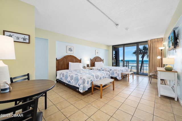 bedroom with light tile patterned flooring, expansive windows, a textured ceiling, and access to outside