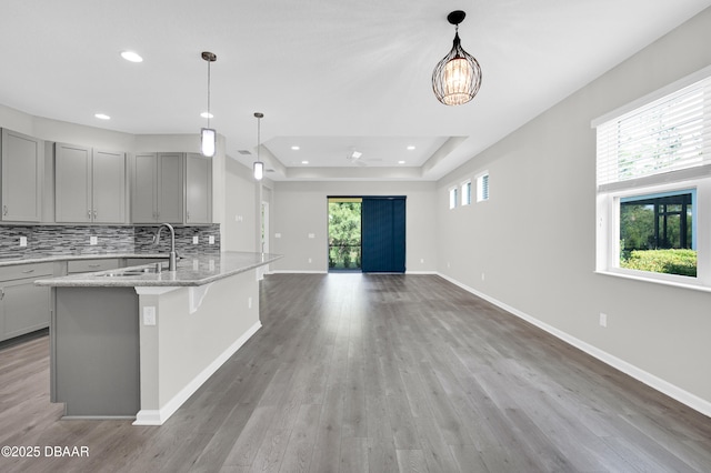304 Coral Reef Way, Daytona Beach, FL 32124 - kitchen featuring wood finished floors, open floor plan, gray cabinets, a sink, and backsplash