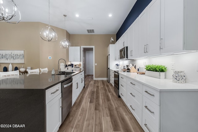 kitchen featuring sink, white cabinets, hanging light fixtures, and appliances with stainless steel finishes