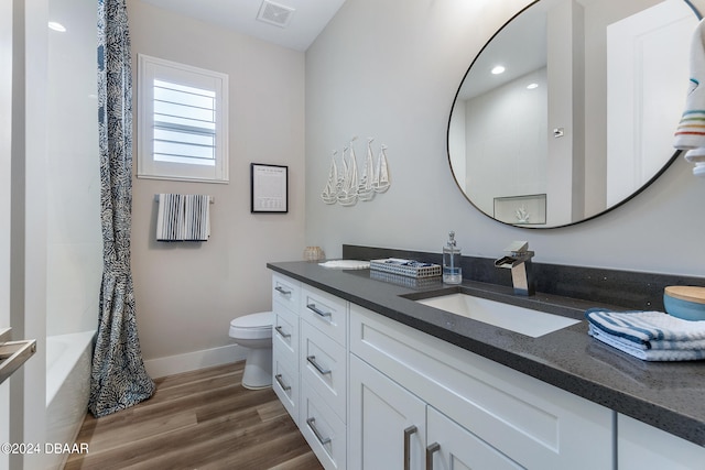 full bathroom featuring hardwood / wood-style flooring, vanity, shower / bath combination with curtain, and toilet